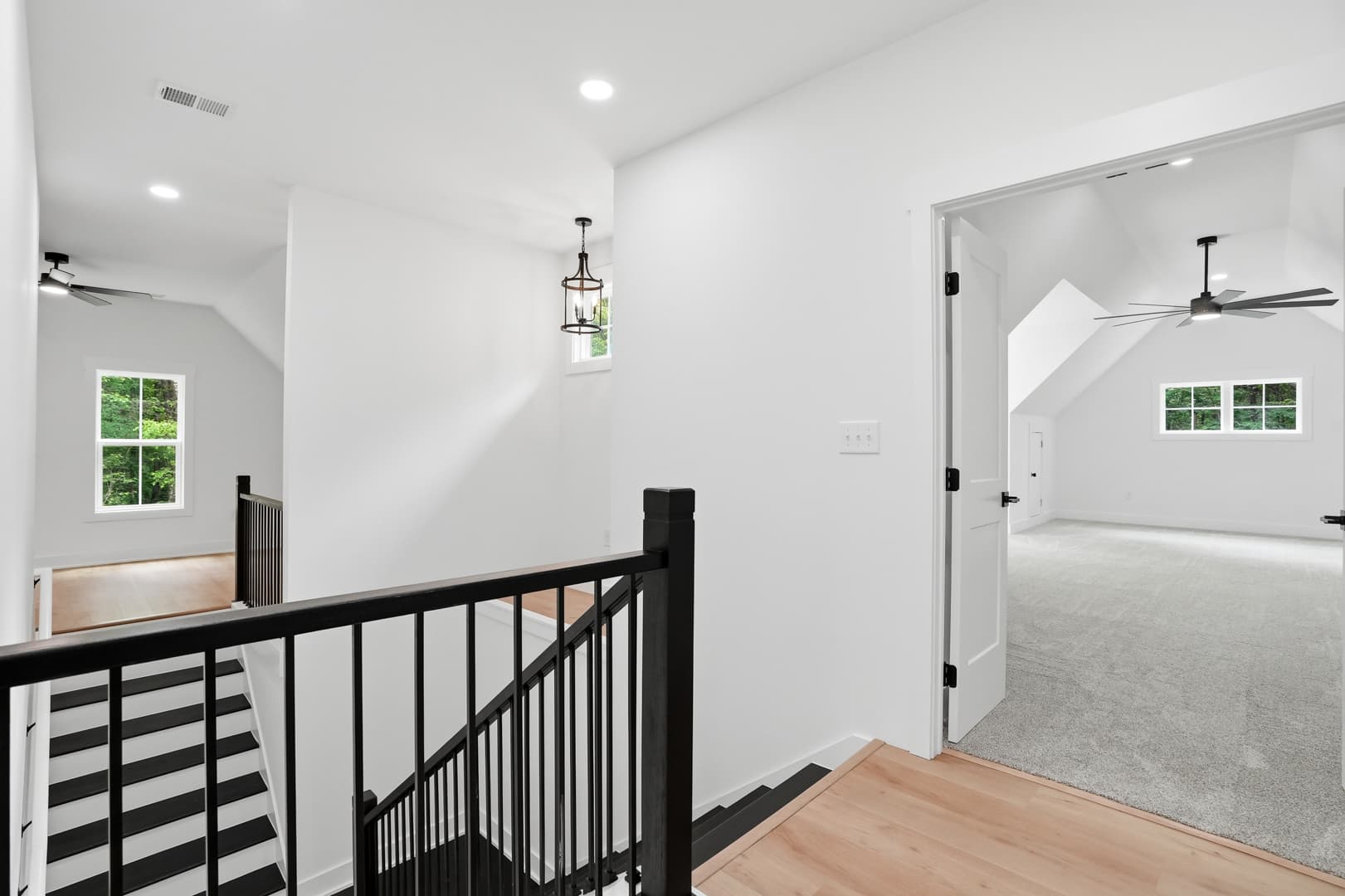 Modern interior featuring black and white striped stairs, white walls, and an open carpeted room.